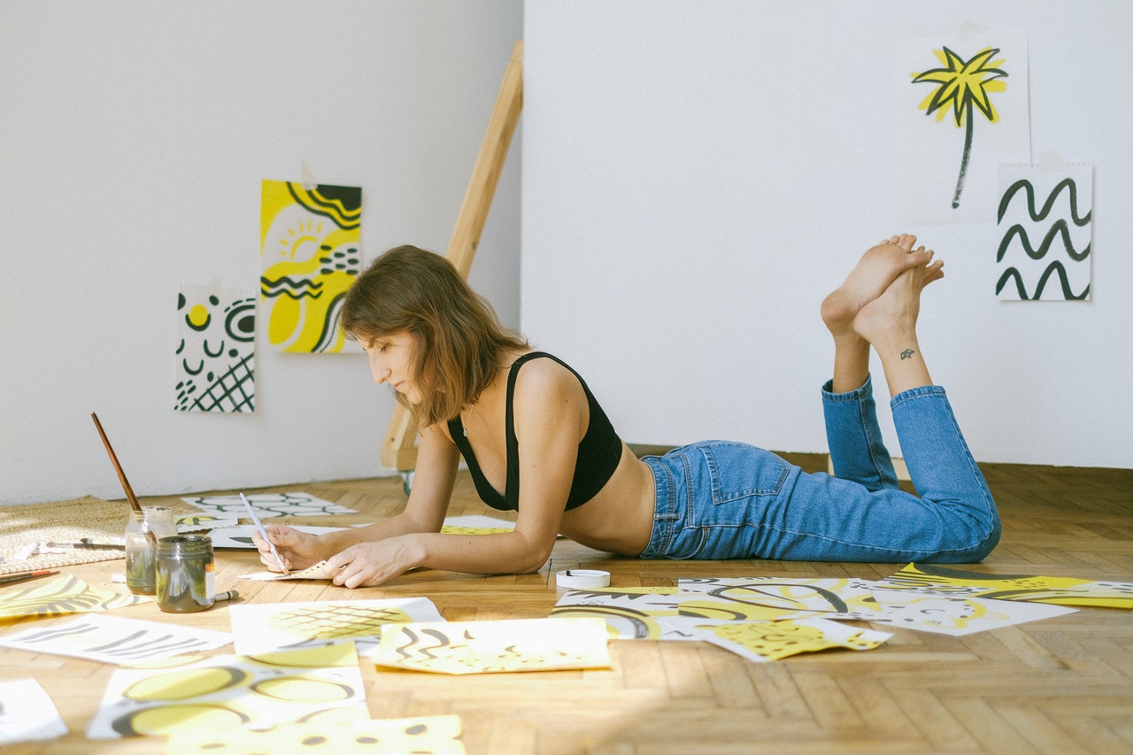 photo of woman lying on the floor and painting to relieve stress