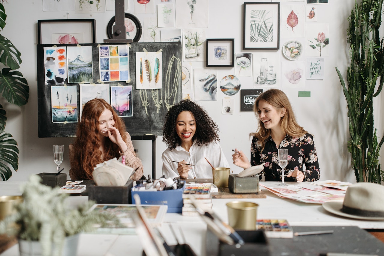 three women happily painting and laughing in their desks