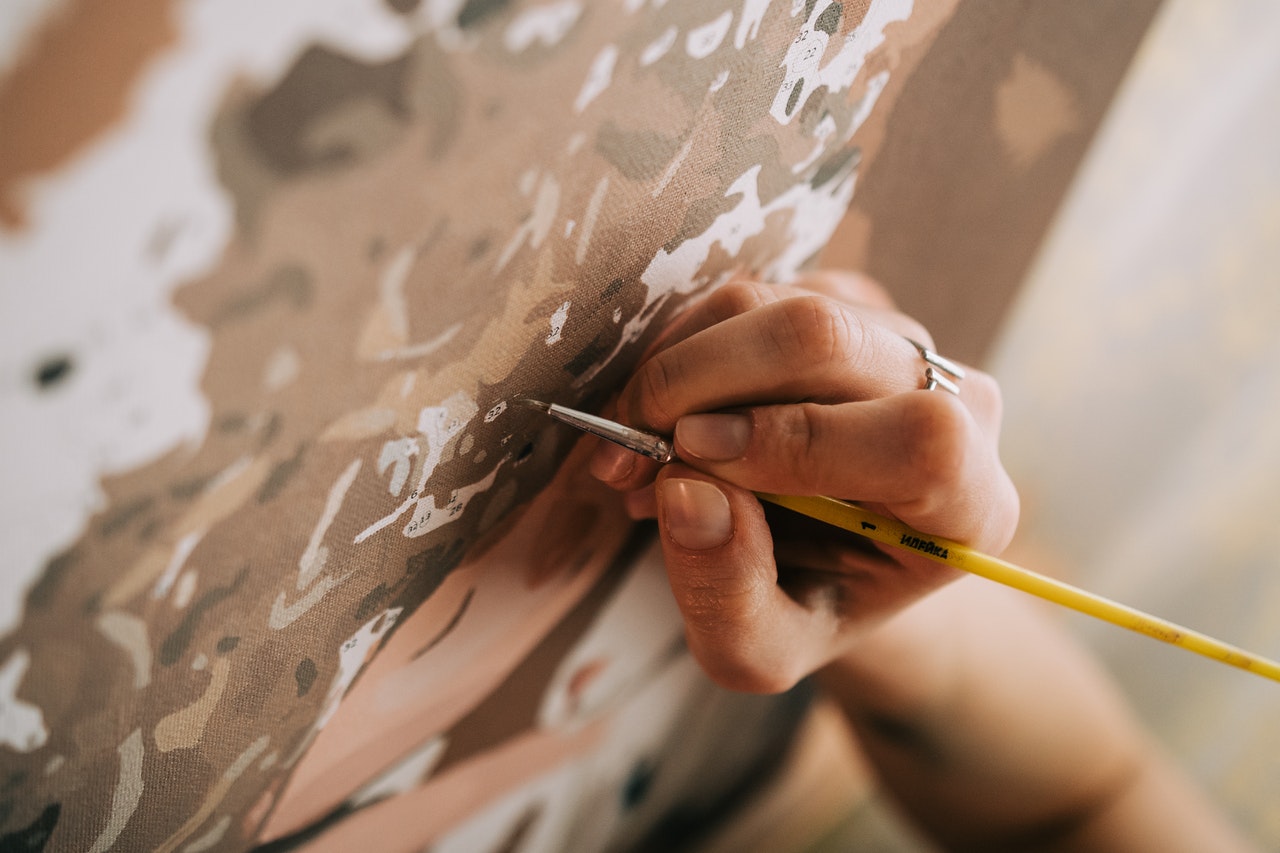 woman holding brush painting custom paint by numbers with acrylic paints