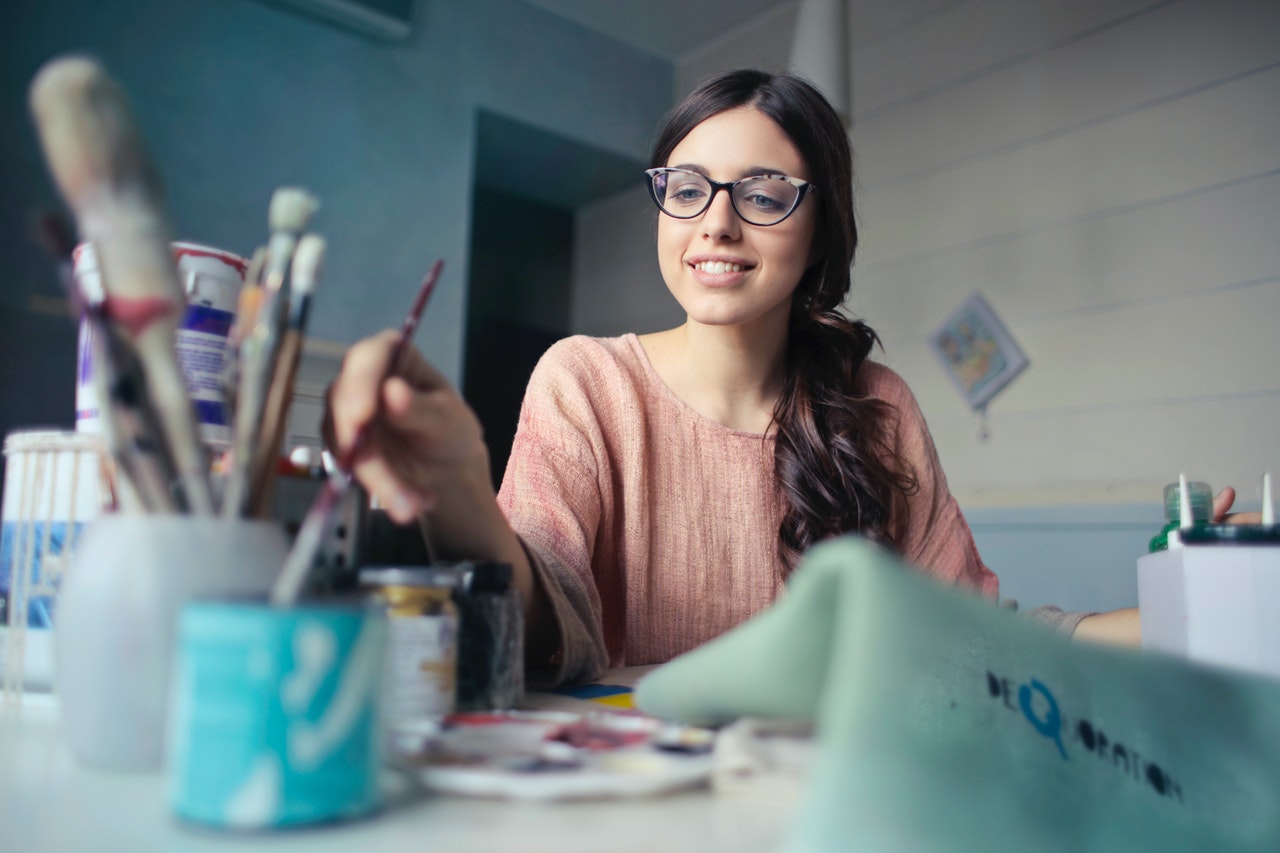 woman in brown shirt holding brush and improving painting